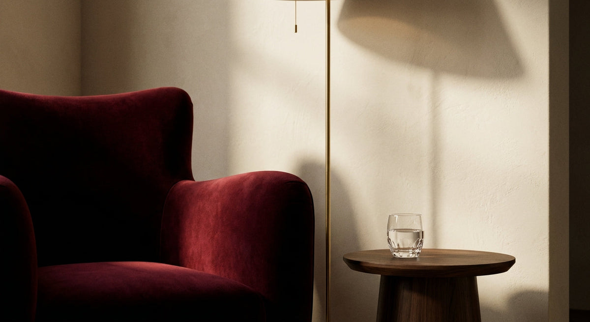 Red armchair next to a small wooden table with a glass on a softly lit room.